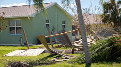 Damaged fence and uprooted trees outside a house after a storm 