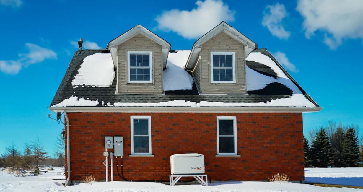 a house with snow on the roof and Generac standby backup home generator installed with a transfer switch in Shanty Bay Ontario